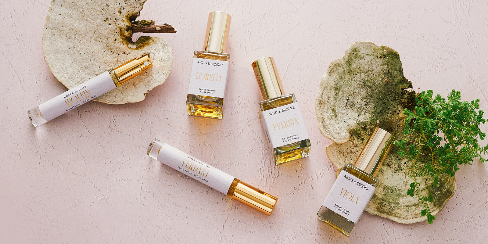 The Moss & Brooke botanical perfume range (featuring minimal packaging and gold foil) sits on a minimal background with lush natural elements.