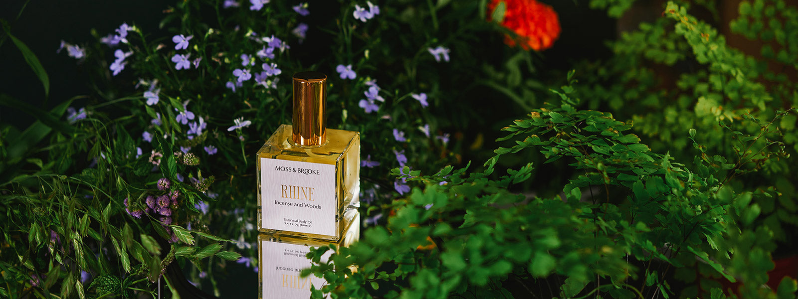 Moss & Brooke body oil sits in a lush flower background.